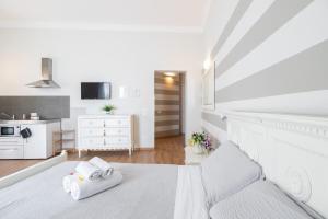 a white bedroom with a white bed and a kitchen at Camera Tua - Falloppio 44 Rooms in Padova