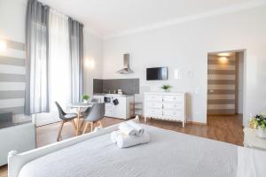 a white bedroom with a bed and a kitchen at Camera Tua - Falloppio 44 Rooms in Padova +46 photos