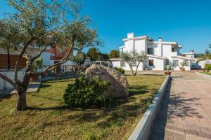 a garden with a rock and a tree and a building at Domo de Iannas-House Live Express in Quartu Sant'Elena