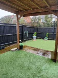 a backyard with a wooden pergola and green grass at Anchored Homes in Spalding