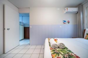 a bedroom with a white bed and a couch at Mares e Flores by OlaMar Bombinhas in Bombinhas