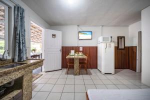 a kitchen with a refrigerator and a table at Mares e Flores by OlaMar Bombinhas in Bombinhas