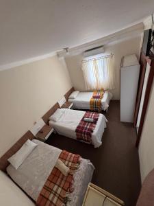 a small room with two beds and a refrigerator at Hotel Norte Sul in Campo Grande