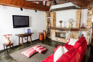 a living room with a red couch and a fireplace at Pousada do Garimpo in Diamantina