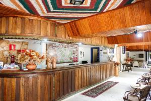 a restaurant with wooden walls and a counter with chairs at Pousada do Garimpo in Diamantina