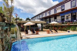 a pool with chairs and umbrellas next to a hotel at Pousada do Garimpo in Diamantina