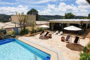 a pool with chairs and umbrellas next to a building at Pousada do Garimpo in Diamantina
