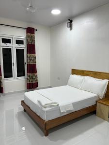 a bedroom with a bed with white walls and a window at Athireege in Manadhoo