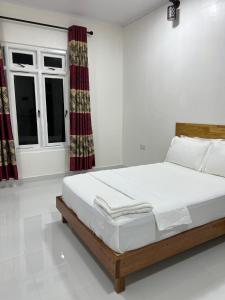a white bedroom with a bed and a window at Athireege in Manadhoo