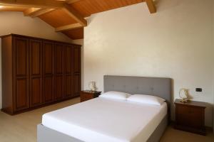 a bedroom with a white bed and wooden cabinets at Resort Helenia in Caulonia