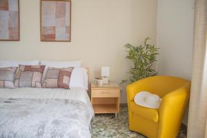 a bedroom with a bed and a yellow chair at Actinia Accommodation in Alghero