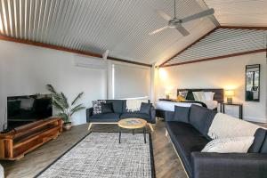 a living room with a couch and a tv at Wallaby Lodges in Pokolbin