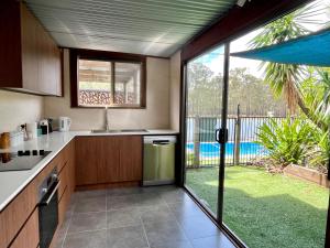 a kitchen with a large sliding glass door to a yard at Wallaby Lodges in Pokolbin +11 photos