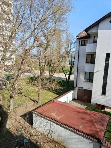 a white building with a red roof next to a tree at Дунав апарт Danube apart in Vidin