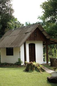 a small white house with a wooden roof at Chácara bello Rio in Guaratuba