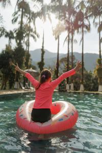 a woman sitting on an inner tube in a swimming pool at Chácara bello Rio in Guaratuba