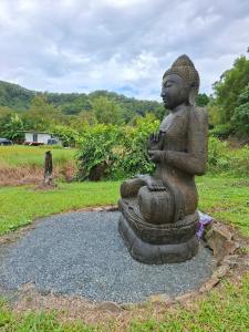 a statue of a buddha sitting on the ground at Haven's Hideaway - Tiny Home in Burringbar