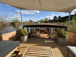a boat on a river with two potted plants at Unique 2 Bed Waterside Retreat Pet Friendly in Upton upon Severn