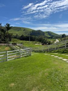 a white fence in a field with mountains in the background at Recanto Catarina in Cunha