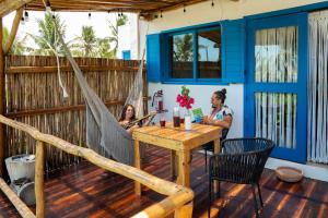 two women sitting in a hammock on a deck at Casa Omero Seaview. in El Cuyo