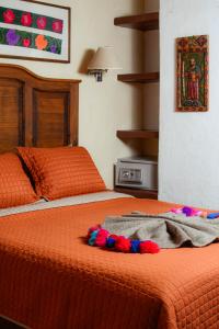 a bed with an orange comforter and a blanket on it at Hotel El Zaguán Histórico in San Cristóbal de Las Casas +37 photos
