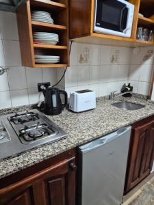 a kitchen with a stove and a sink and a microwave at Colorina Bariloche en edificio Bariloche Center in San Carlos de Bariloche