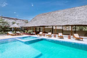 a villa with a swimming pool in front of a building at Farashuu Luna Hotel in Kendwa