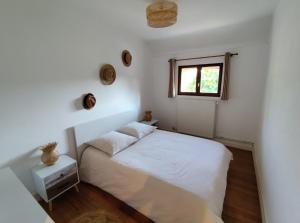a white bedroom with a bed and a window at La Ronce maison d hote - piscine SPA in Rouvres