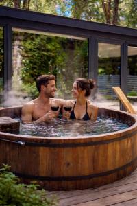 a man and woman sitting in a hot tub with wine glasses at Calma Lodge in Puerto Clocker