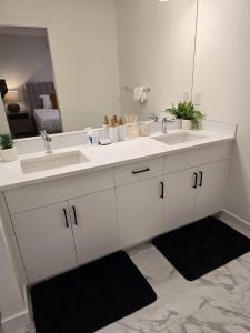 a white bathroom with two sinks and a mirror at Modern Comfort - With AC in Calgary +112 photos