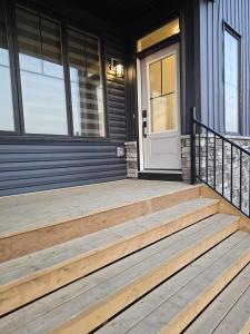 a front porch with wooden stairs and a white door at Modern Comfort - With AC in Calgary