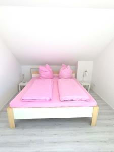 a white bed with pink sheets and pillows on it at Ferienwohnung Groß-Umstadt in Groß-Umstadt