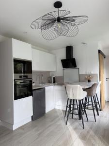 a kitchen with white cabinets and a ceiling fan at Le Refuge Douillet à 10min de Disneyland avec Parking Privé et Belle terrasse vue sur Jardin in Coupvray