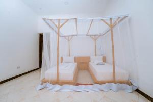 a room with two beds and a canopy at Farashuu Luna Hotel in Kendwa