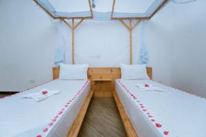 two beds in a room with white sheets and red roses at Farashuu Luna Hotel in Kendwa