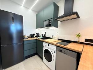 a kitchen with green cabinets and a washer and dryer at ZELUN Suite Torremolinos Center in Torremolinos