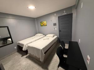 a bedroom with two beds and a table and a door at 2367 Belém Residence in Belém
