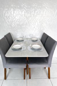 a table with two plates and glasses on it at Casa completa, aconchegante com ar condicionado in Montes Claros