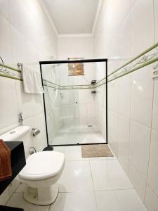 a white bathroom with a shower and a toilet at Casa completa, aconchegante com ar condicionado in Montes Claros +7 photos