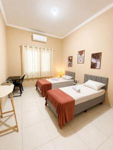 a bedroom with two beds and a table and a desk at Casa completa, aconchegante com ar condicionado in Montes Claros