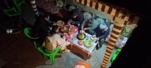 a group of people sitting at a table with food at Gite ousalem timichi in Timichchi