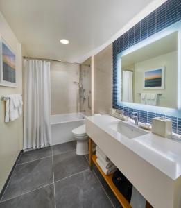 a bathroom with a sink and a toilet and a mirror at Renaissance Honolulu Hotel & Spa in Honolulu