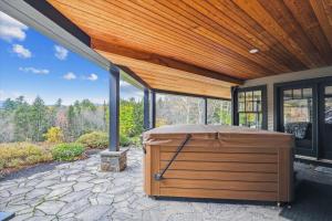 a hot tub sitting under a wooden roof on a patio at Weeks Hill Meadows in Stowe