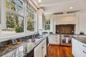 a kitchen with white cabinets and a sink and windows at Weeks Hill Meadows in Stowe