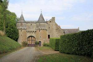 an old castle with a road in front of it at Gîte Baumelin près de Dinan in Guenroc