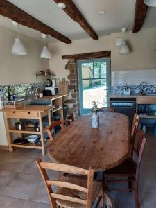 a kitchen with a wooden table and some chairs at Gîte Baumelin près de Dinan in Guenroc