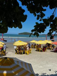 a beach with yellow umbrellas and people on the beach at Chalé Maresia Maranduba in Maranduba