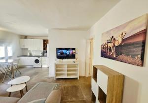 a living room with a couch and a tv on a wall at Bungalow Alma Playa Roca in Costa Teguise