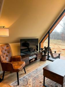 a living room with a television and a chair at Bison Farm - Cabin Brisa in Culpeper