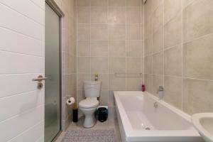 a bathroom with a toilet and a tub and a sink at The Greenlee Grove in Sandton